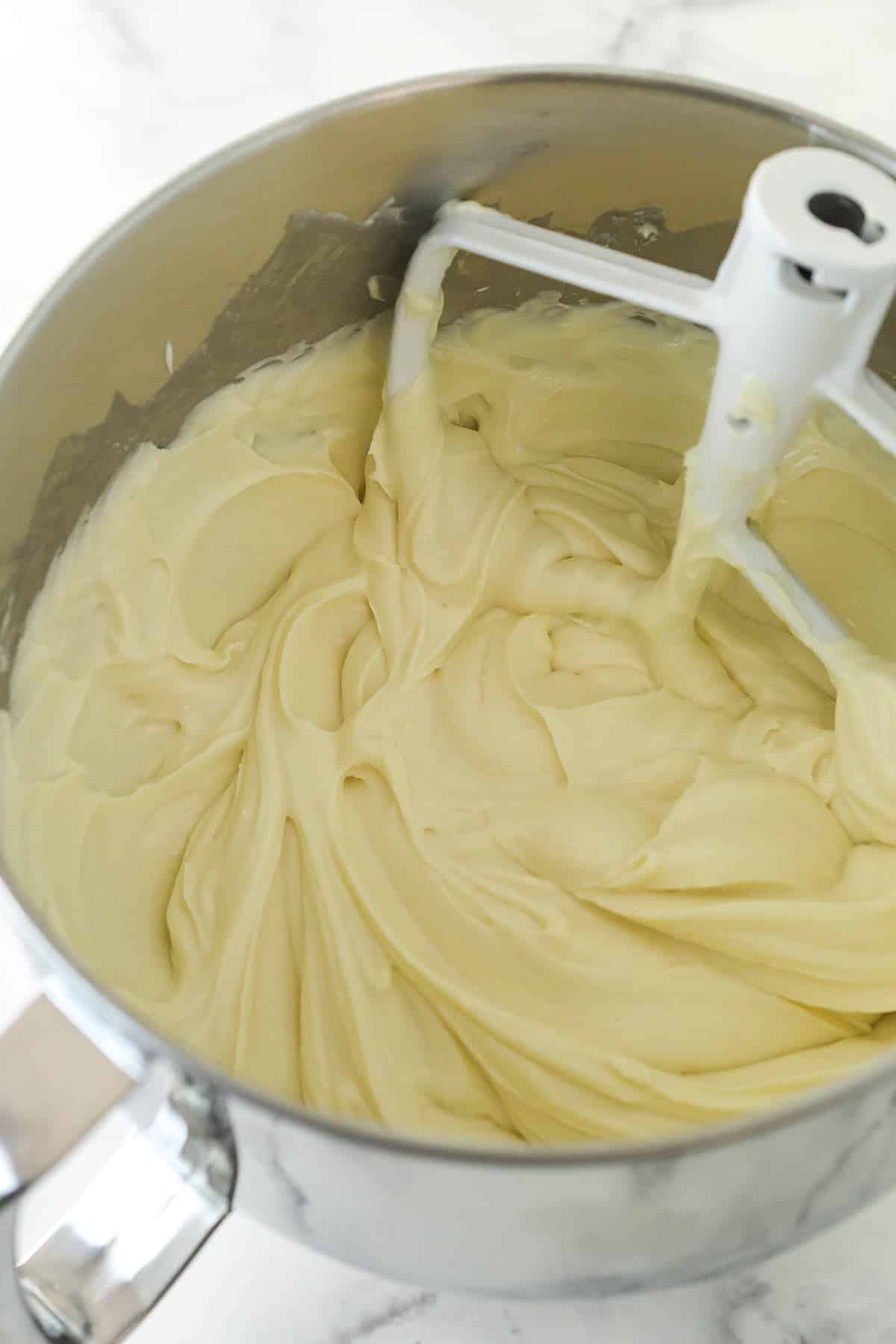 Mixing sour cream and vanilla into a cream cheese mixture for cheesecake filling.