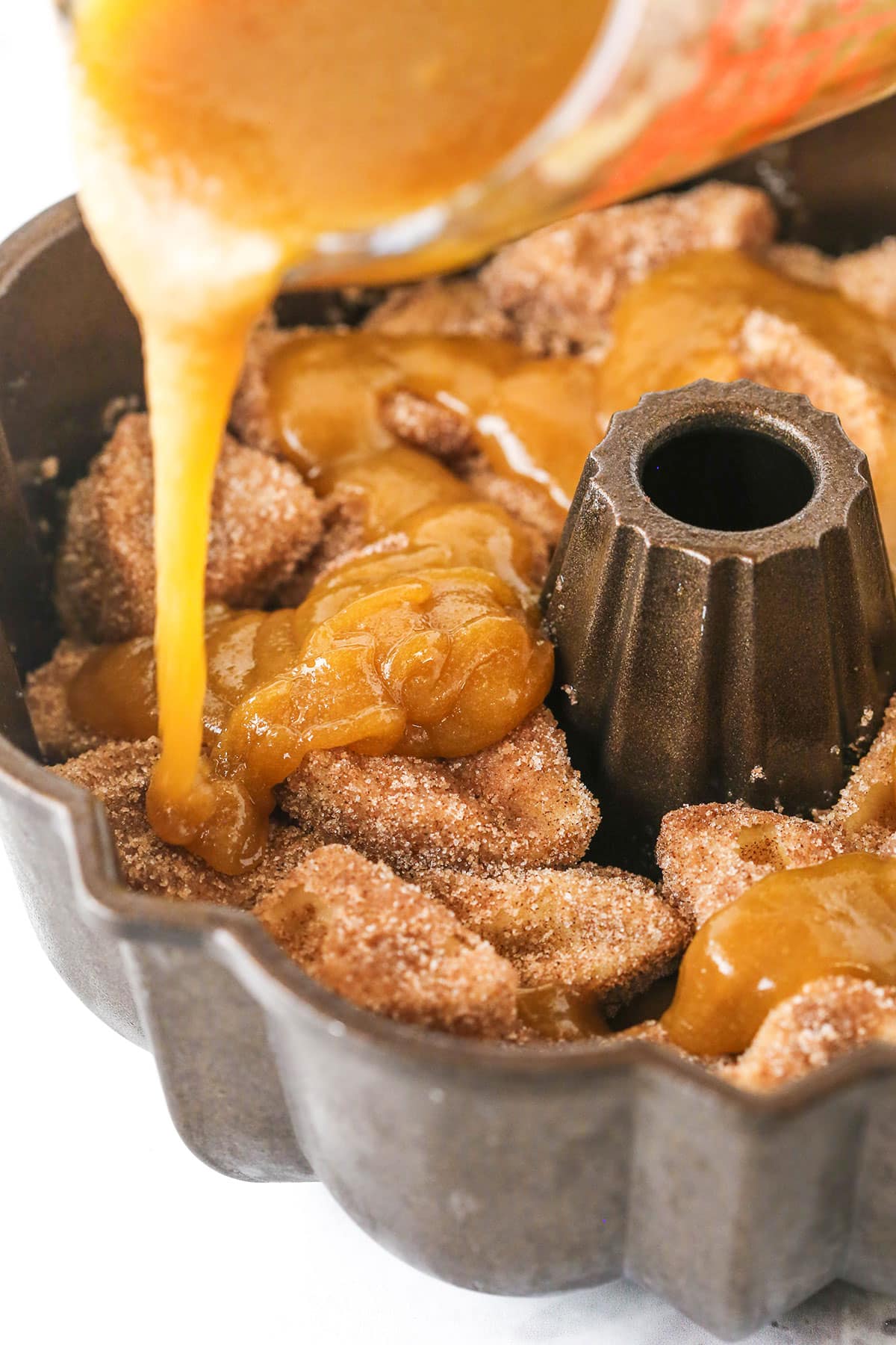 Making Monkey Bread Step showing the buttery sugar sauce being poured over the layered biscuit pieces