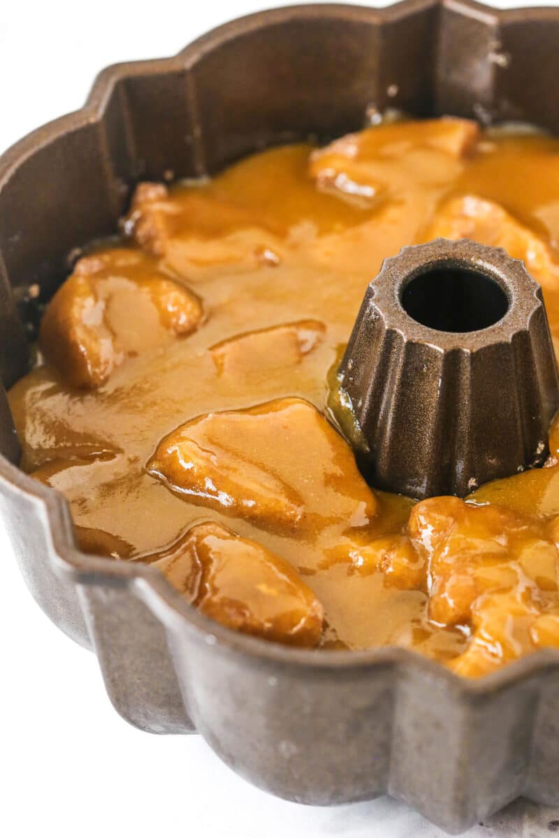 This EASY Monkey Bread recipe is made with balls of refrigerated cookie dough rolled in cinnamon-sugar and coated with brown sugar sauce. Making Monkey Bread Step showing the buttery sugar sauce being poured over the layered biscuit pieces