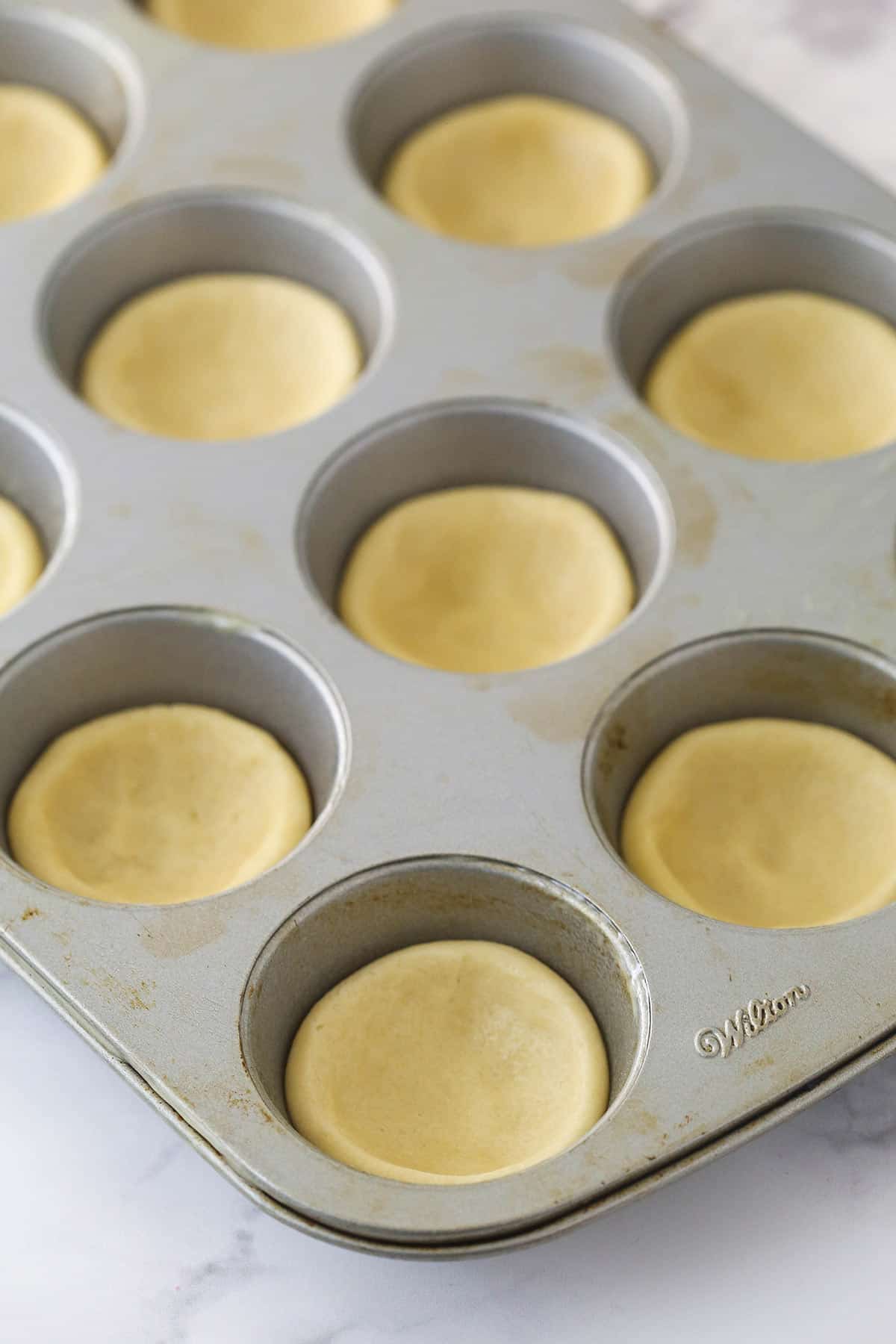 Sugar cookie dough pressed into cupcake tins ready to bake.