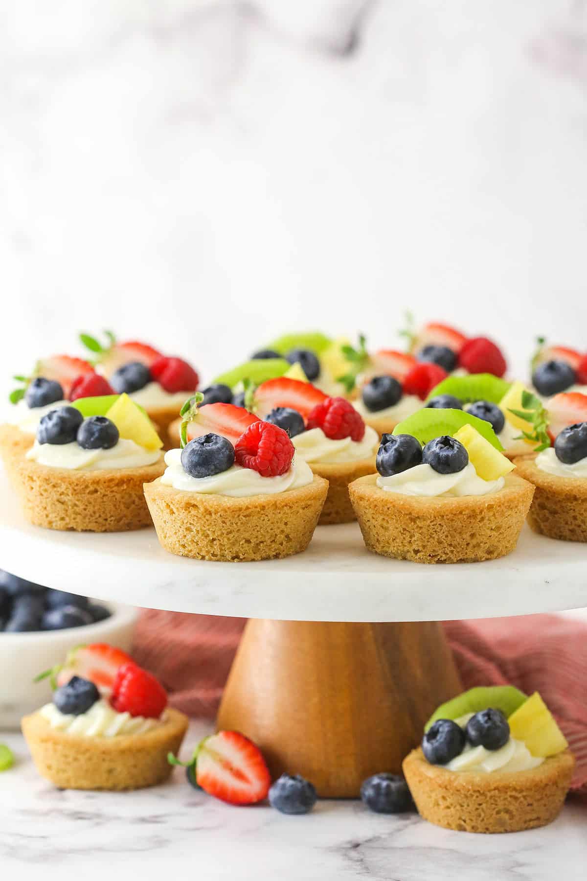 Easy fruit cheesecake sugar cookie cups arranged on a cake platter.