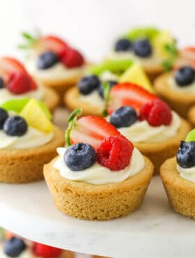 Easy fruit cheesecake sugar cookie cups arranged on a cake platter.