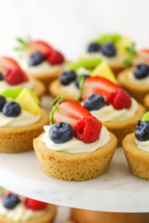 Easy fruit cheesecake sugar cookie cups arranged on a cake platter.