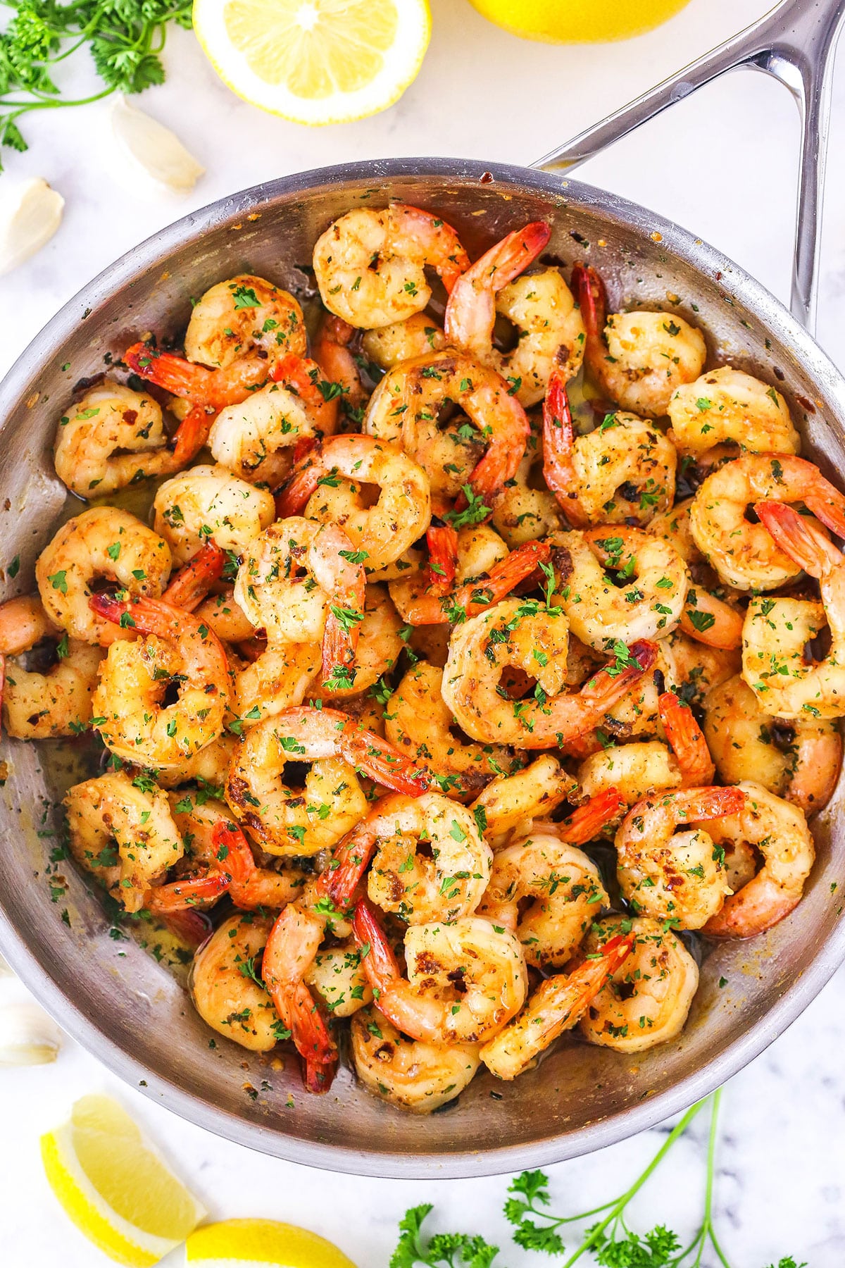 Overhead view of Garlic Butter Shrimp Scampi in a metal pan with cut lemons in the background