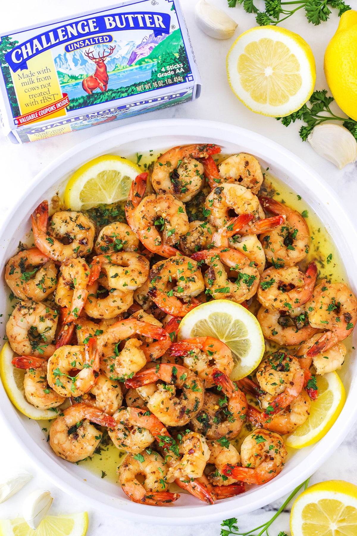 Overhead view of Garlic Butter Shrimp Scampi in a white platter with cut lemons in the background