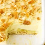Homemade Banana Pudding topped with crushed vanilla wafers in a white platter with one serving removed