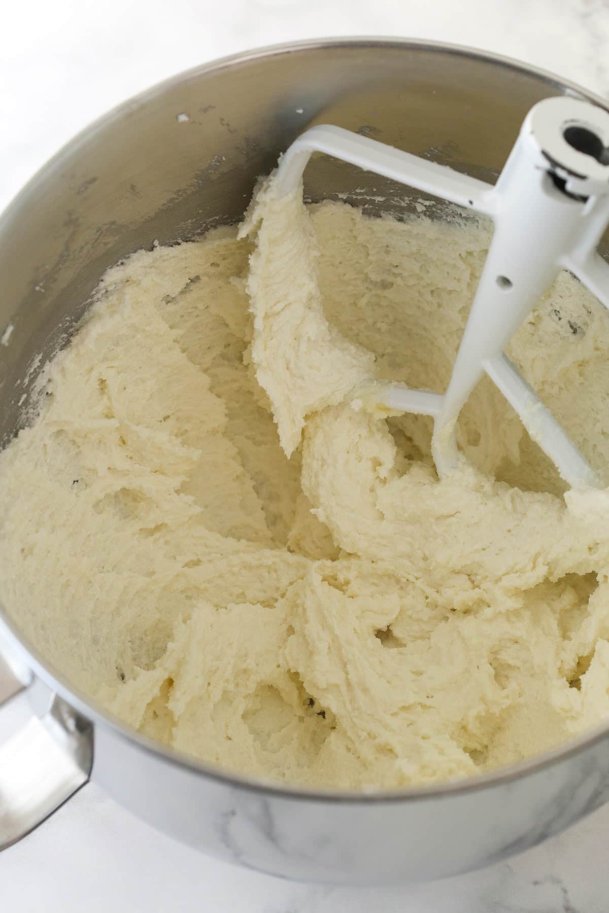 Creaming together butter, shortening, sugar, and vanilla for cake batter.