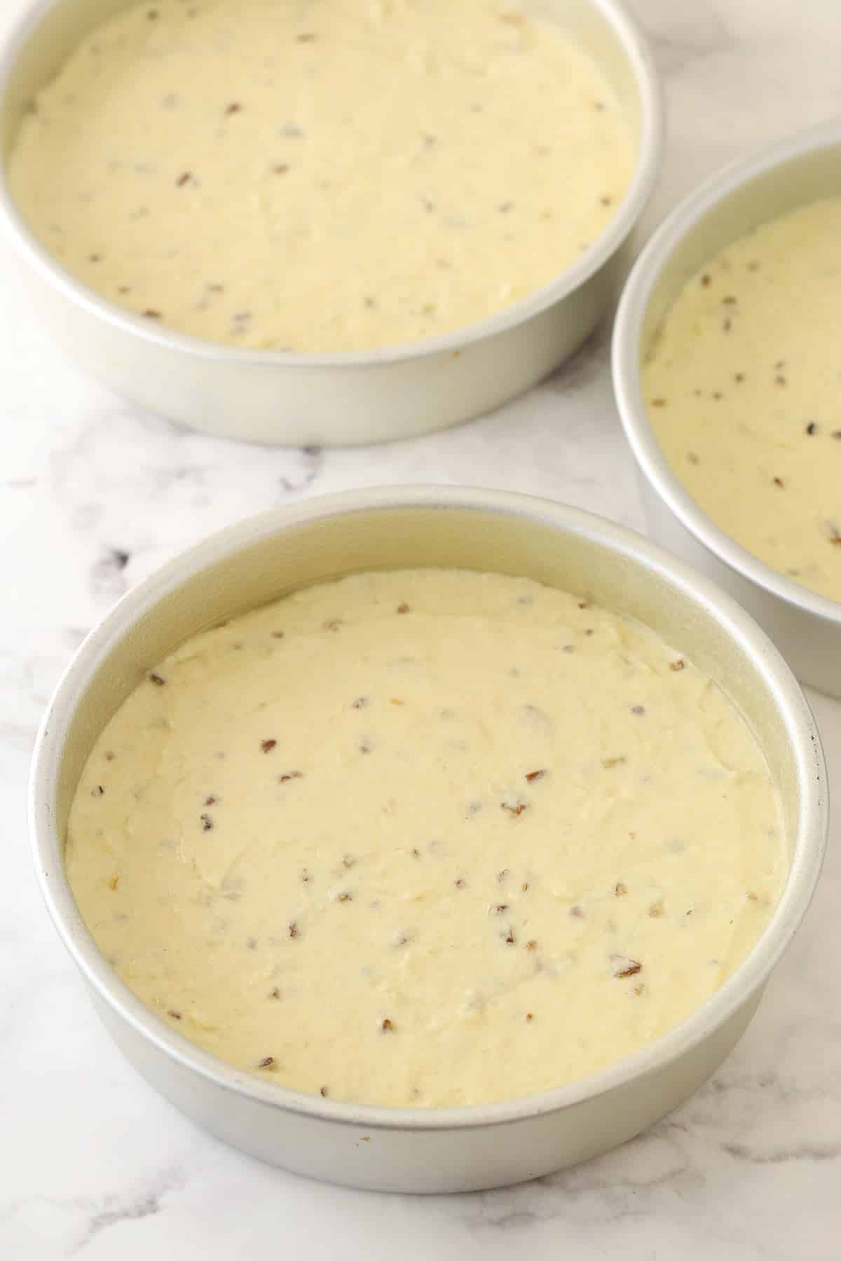 Three cake pans filled with cake batter.