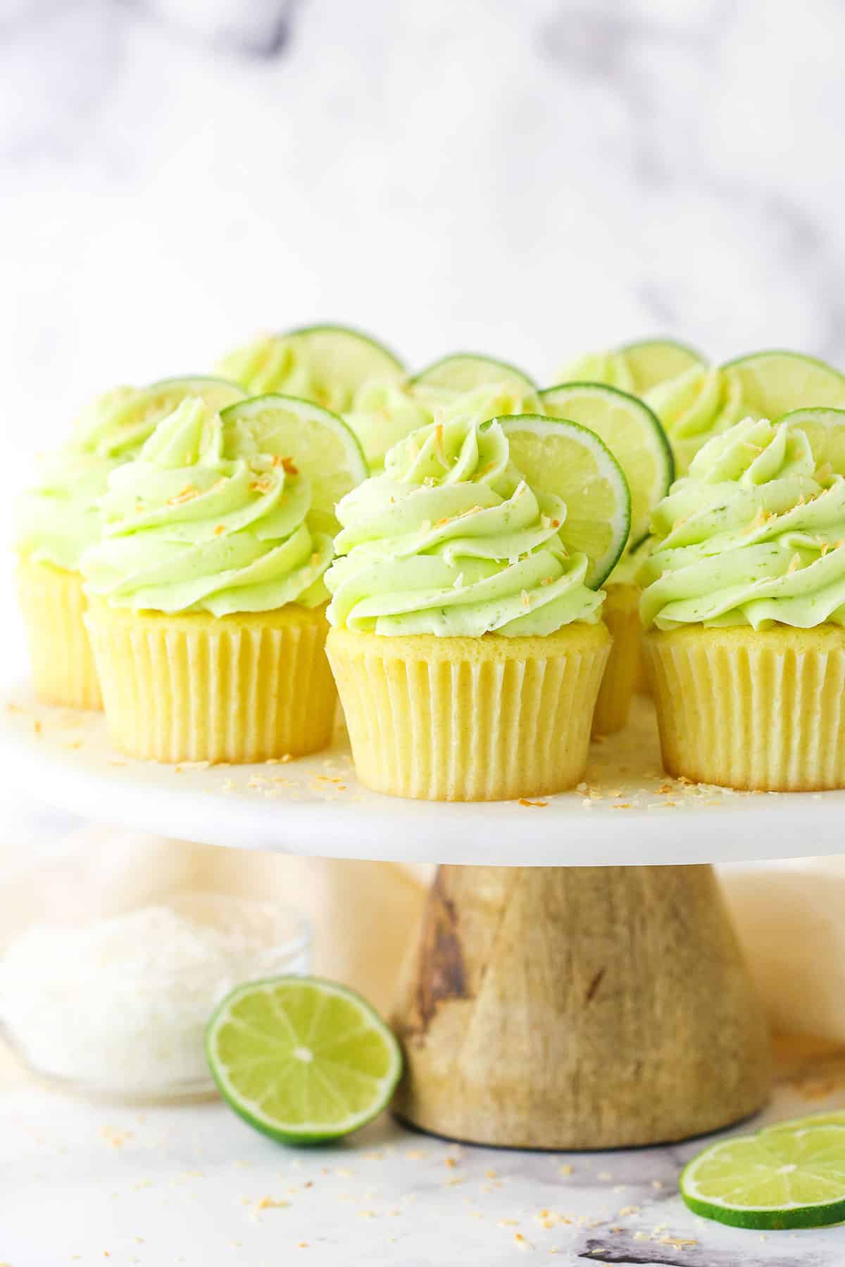 Side view of Key Lime Coconut Cupcakes on a cake stand