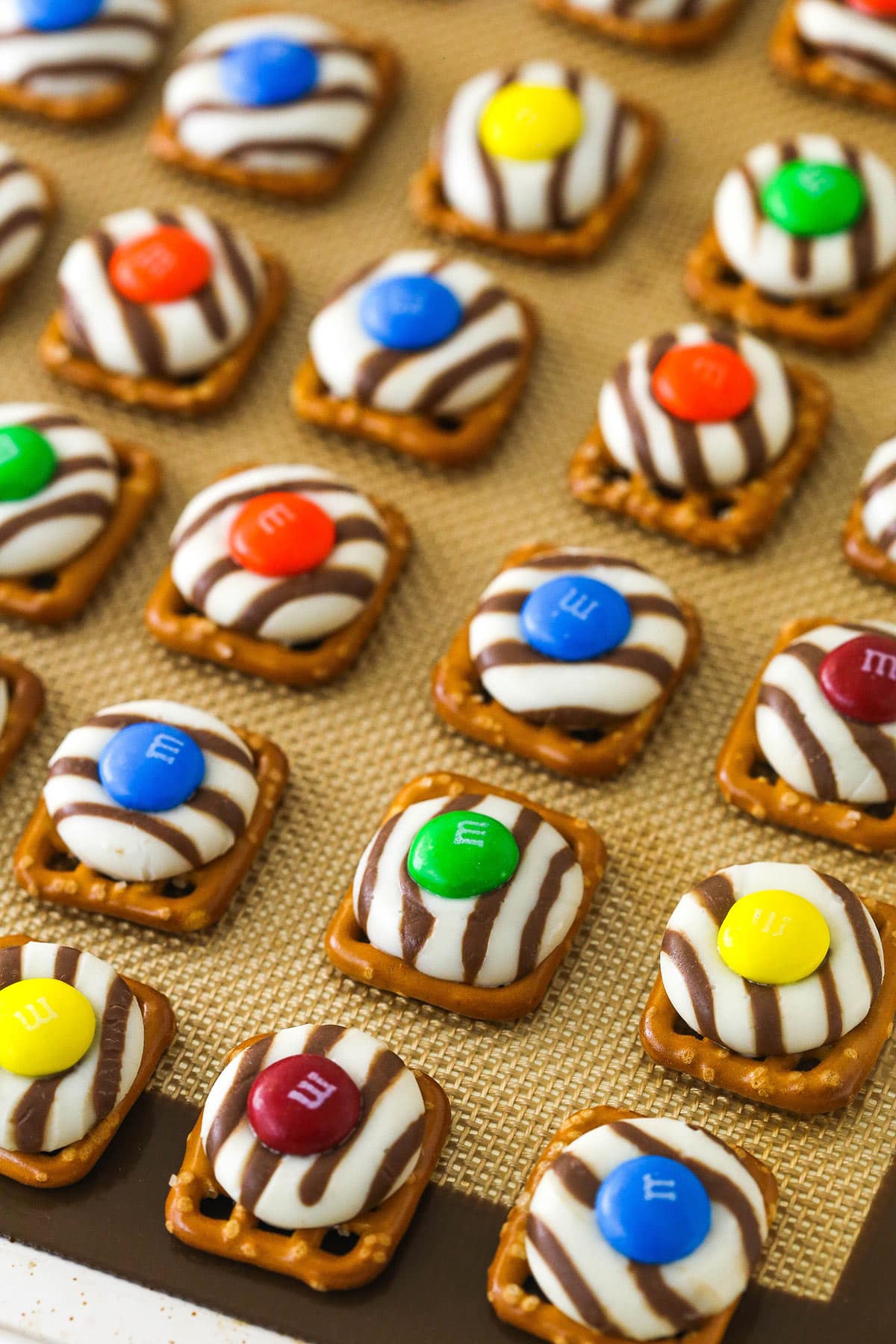 finished pretzel hugs with M&MS on top on silicone baking mat