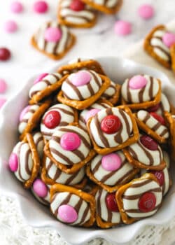 pink and red valentine's day pretzel M&M hugs in a white ruffle bowl