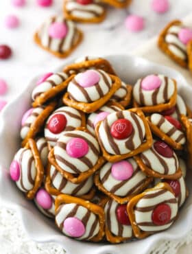 pink and red valentine's day pretzel M&M hugs in a white ruffle bowl