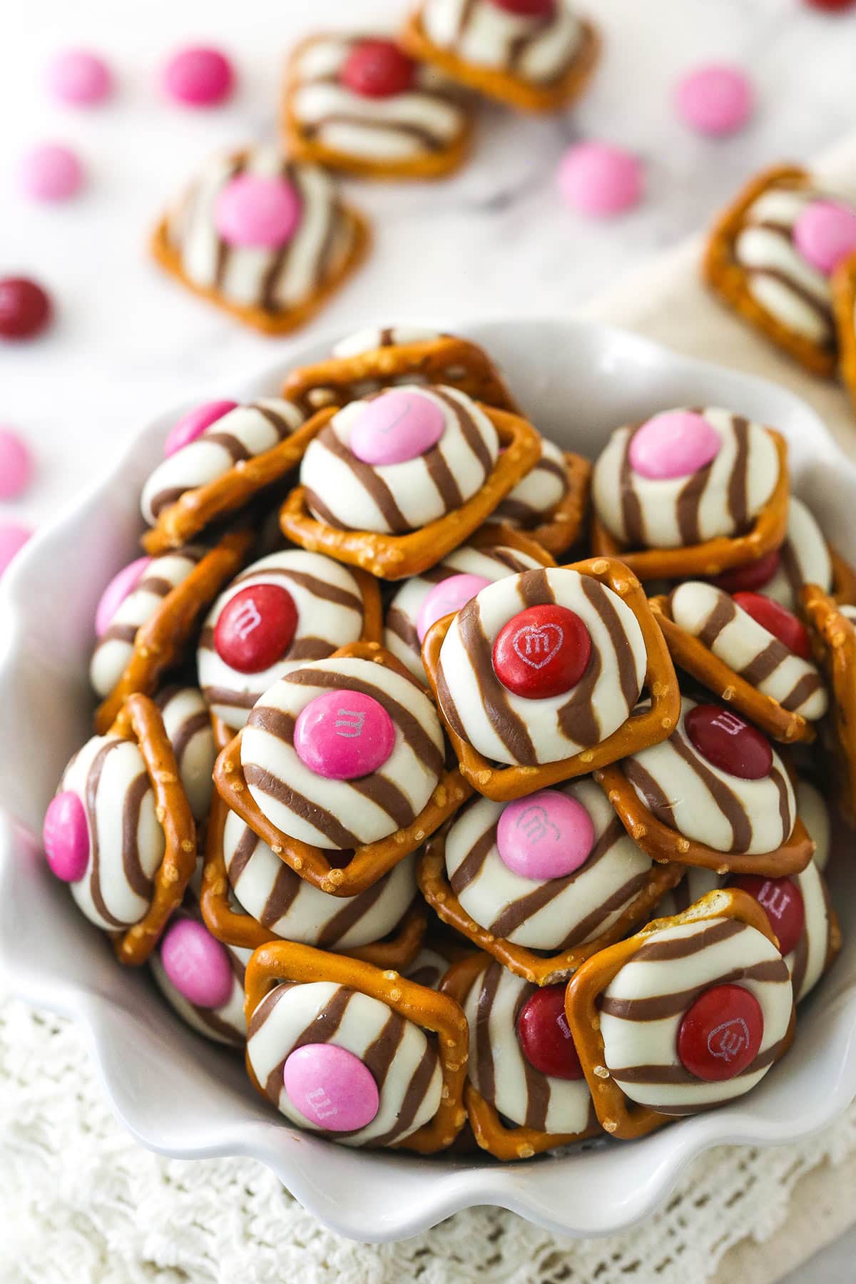 pink and red valentine's day pretzel M&M hugs in a white ruffle bowl