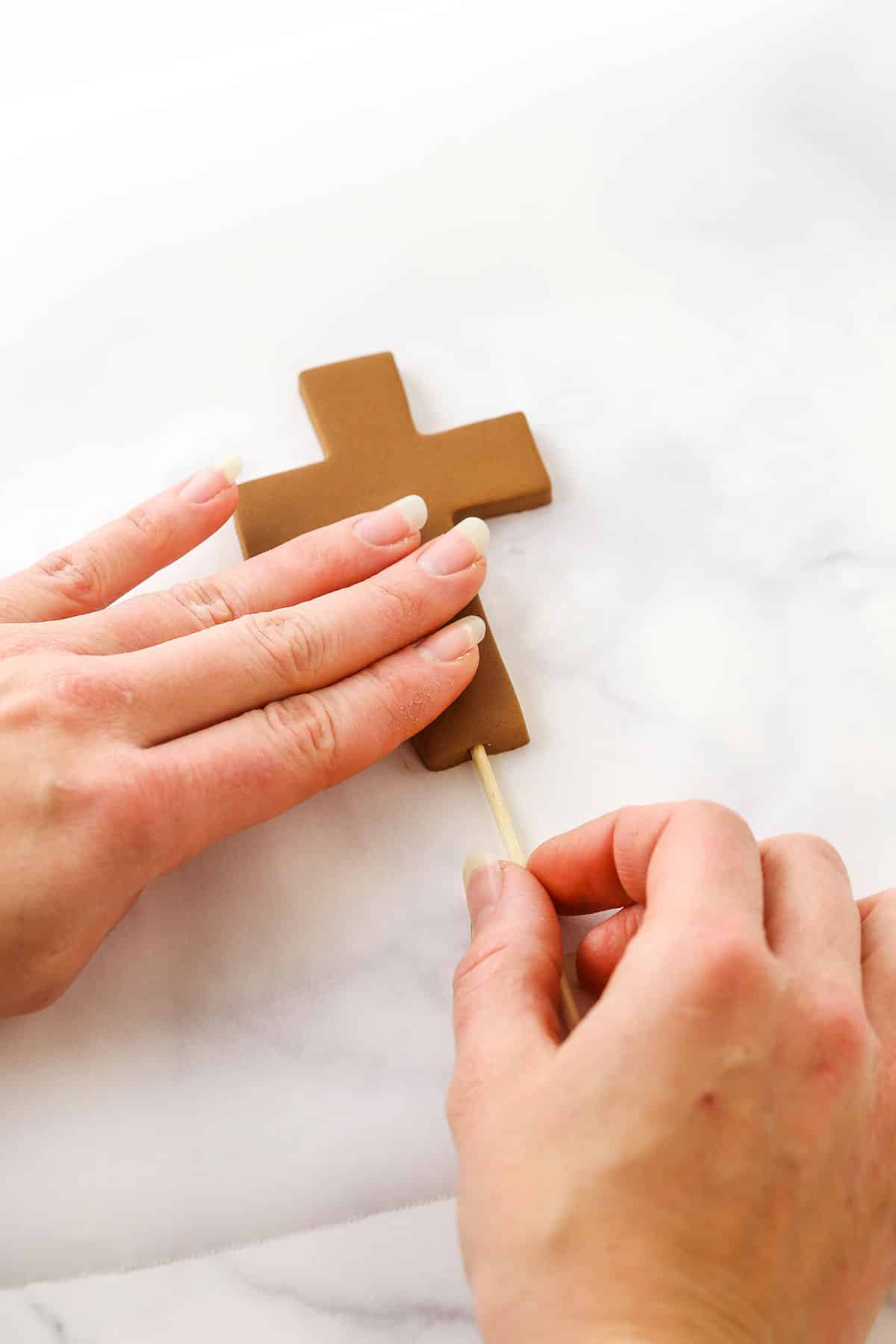 A step in making a Resurrection Cake showing inserting the skewer into the bottom of the cross