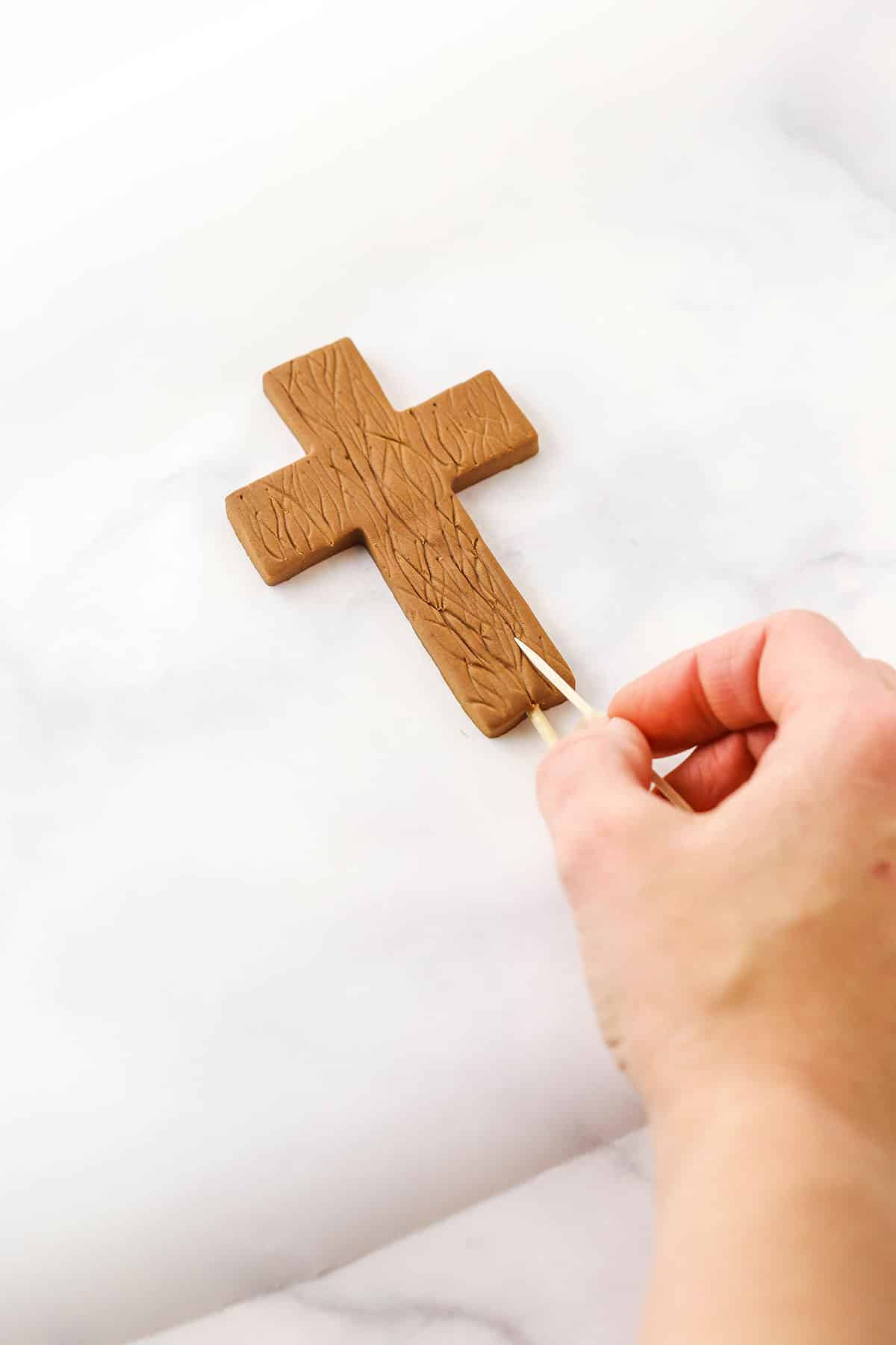 A step in making a Resurrection Cake showing the use of a toothpick to texturize the cross