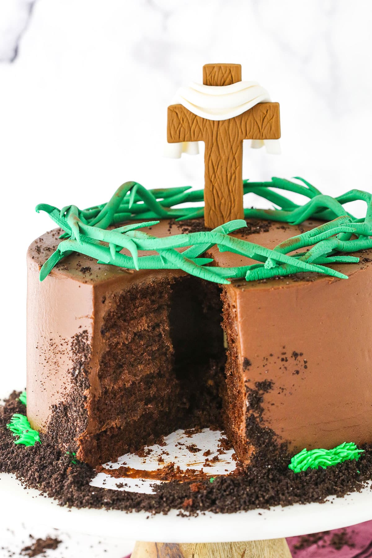 Side view of a Resurrection Cake with a slice removed and decorated with a fondant cross and crown of thorns