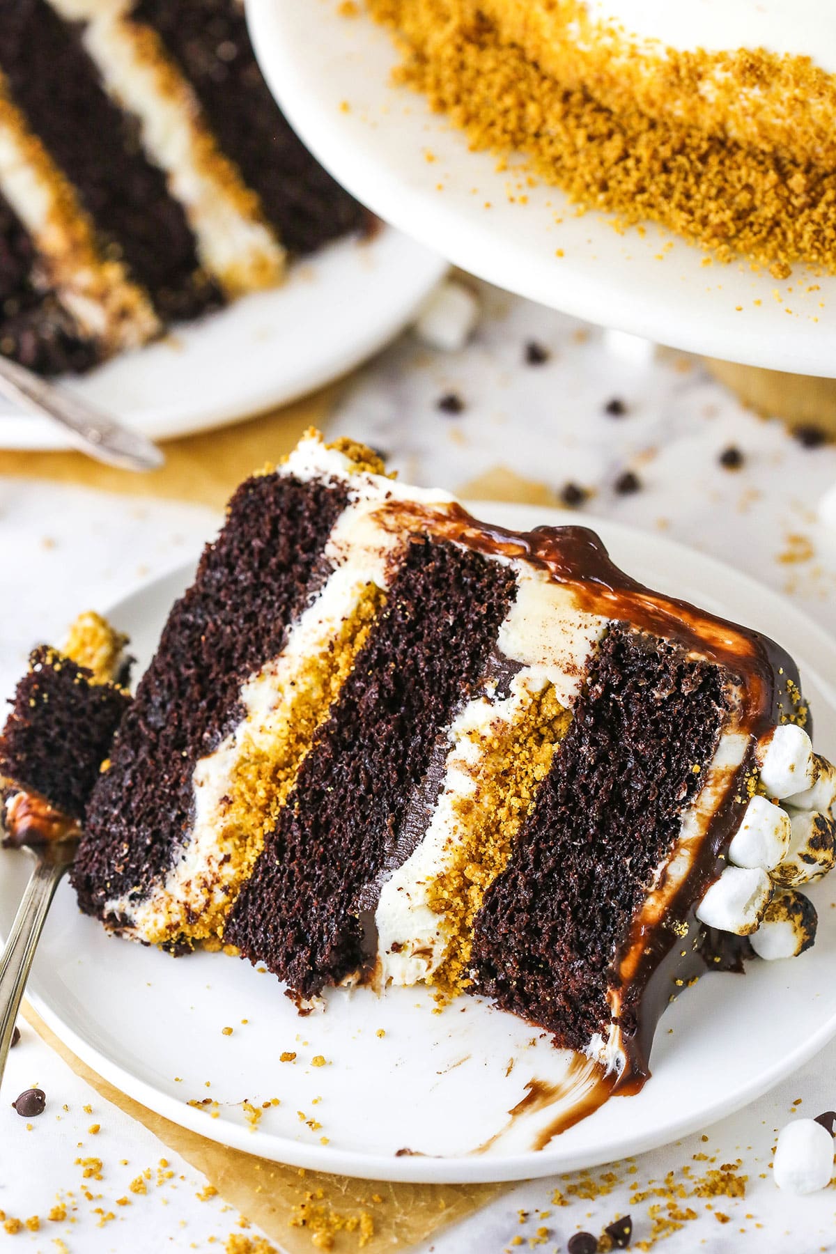 A slice of S'mores Cake with a bite removed and a fork on a white plate