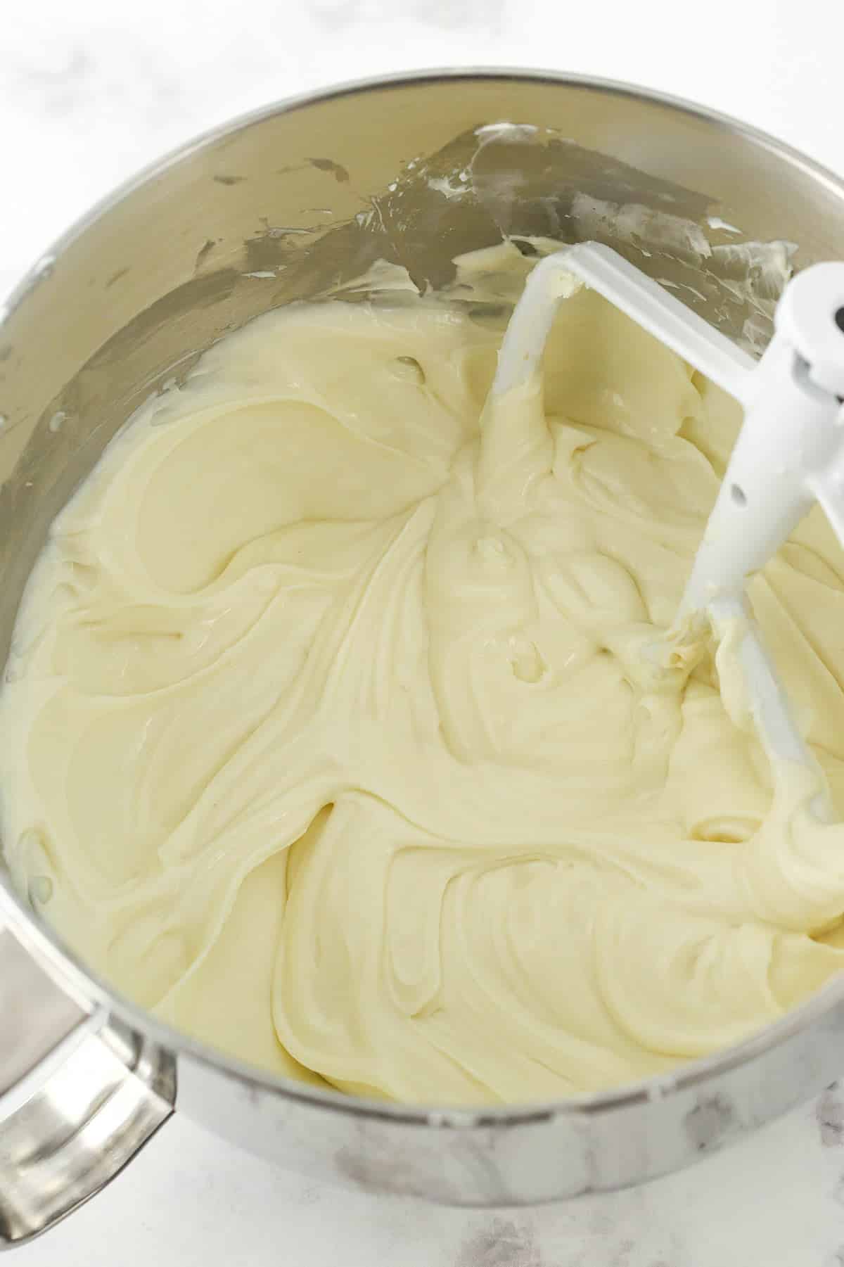 Adding sour cream and vanilla to cheesecake filling.