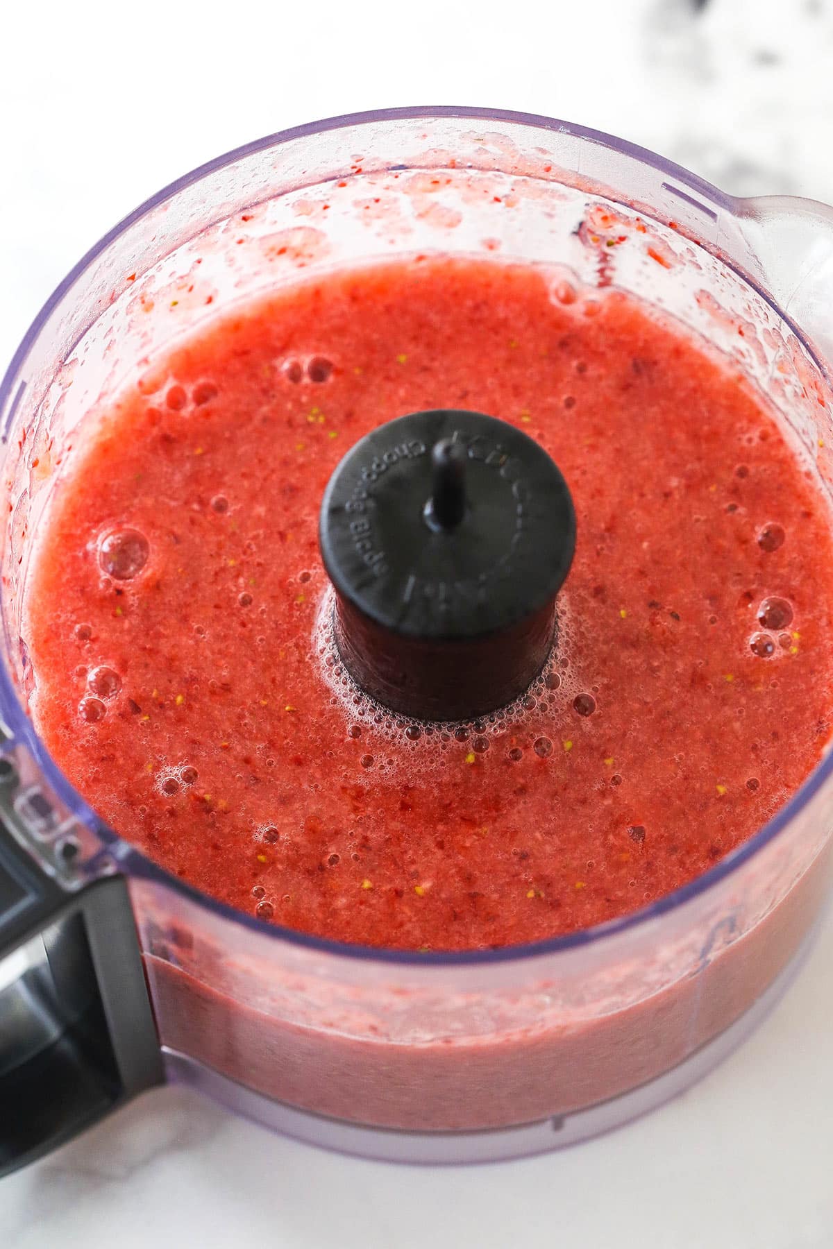 Pureeing strawberries in a food processor.