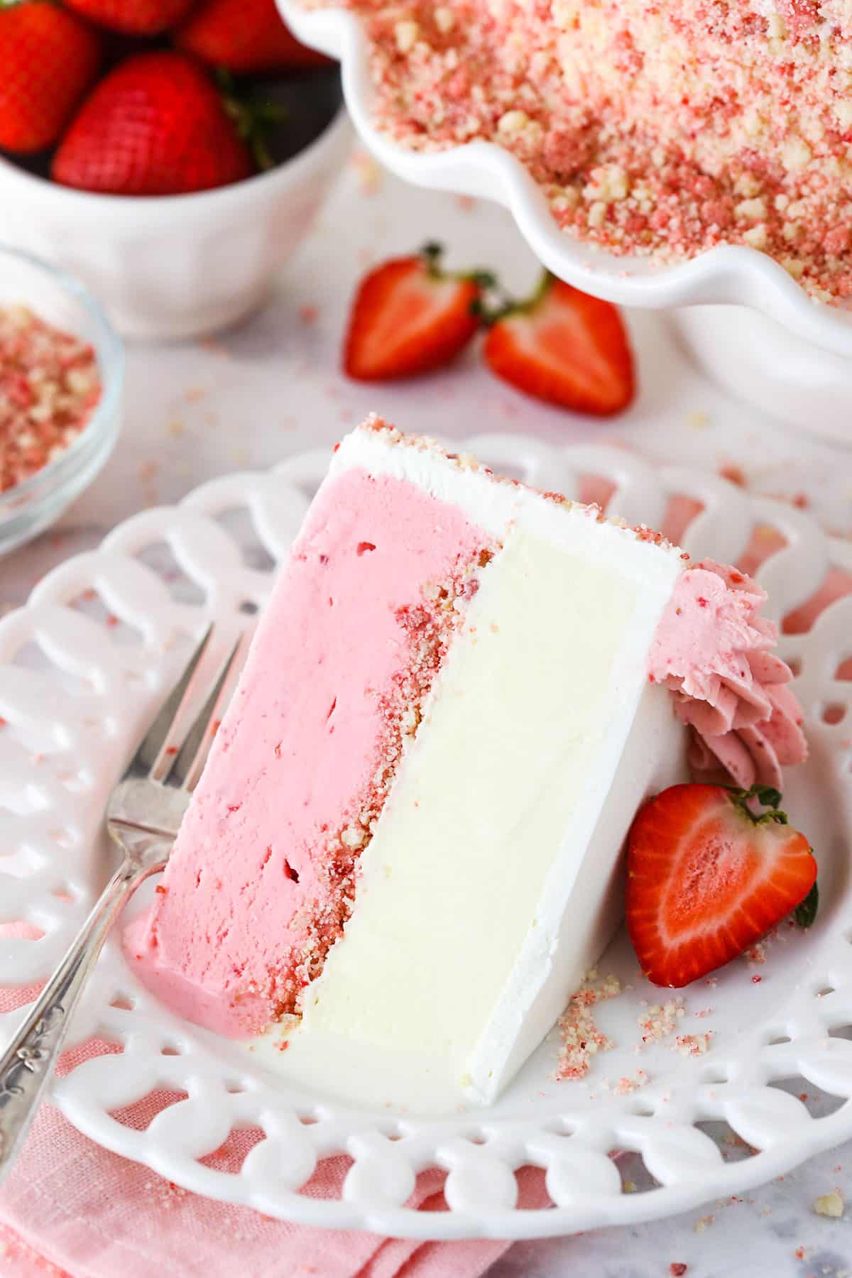 A slice of Strawberry Crunchie Ice Cream Cake on a white plate with a fork