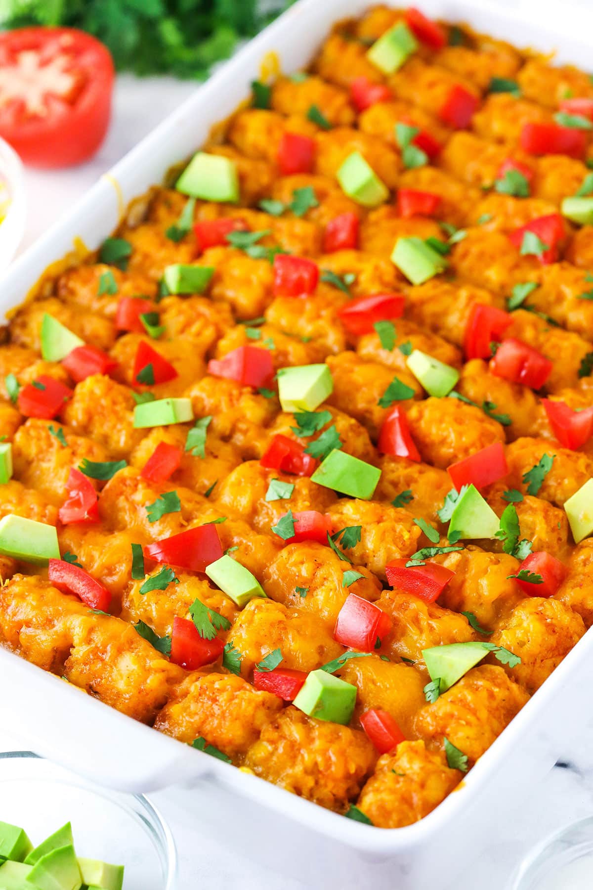 Taco Tater Tot Casserole with chopped avocado and tomato on top in a white platter