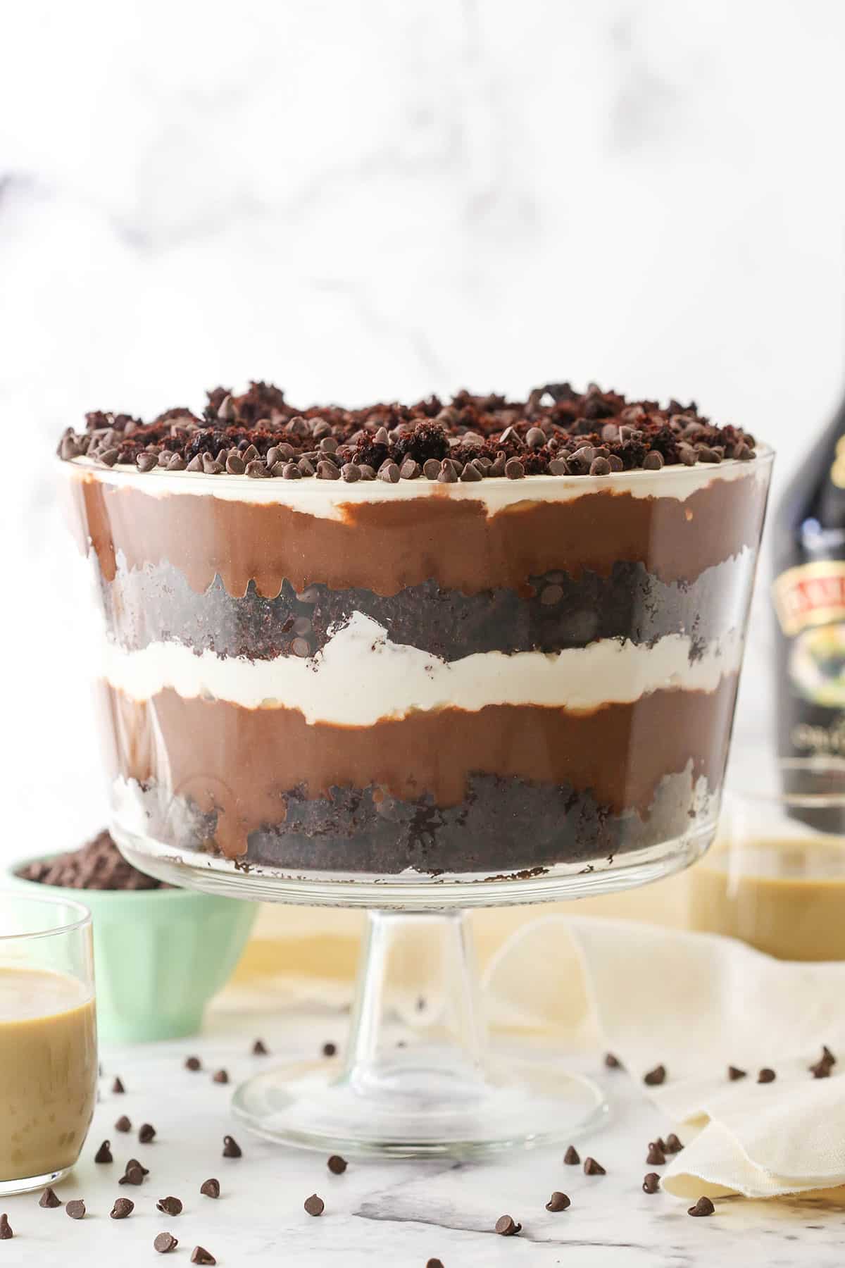 Side view of a full Baileys Chocolate Trifle in a glass trifle stand topped with chocolate chips