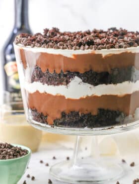 Side view of a full Boozy Baileys Chocolate Trifle in a glass trifle stand topped with chocolate chips
