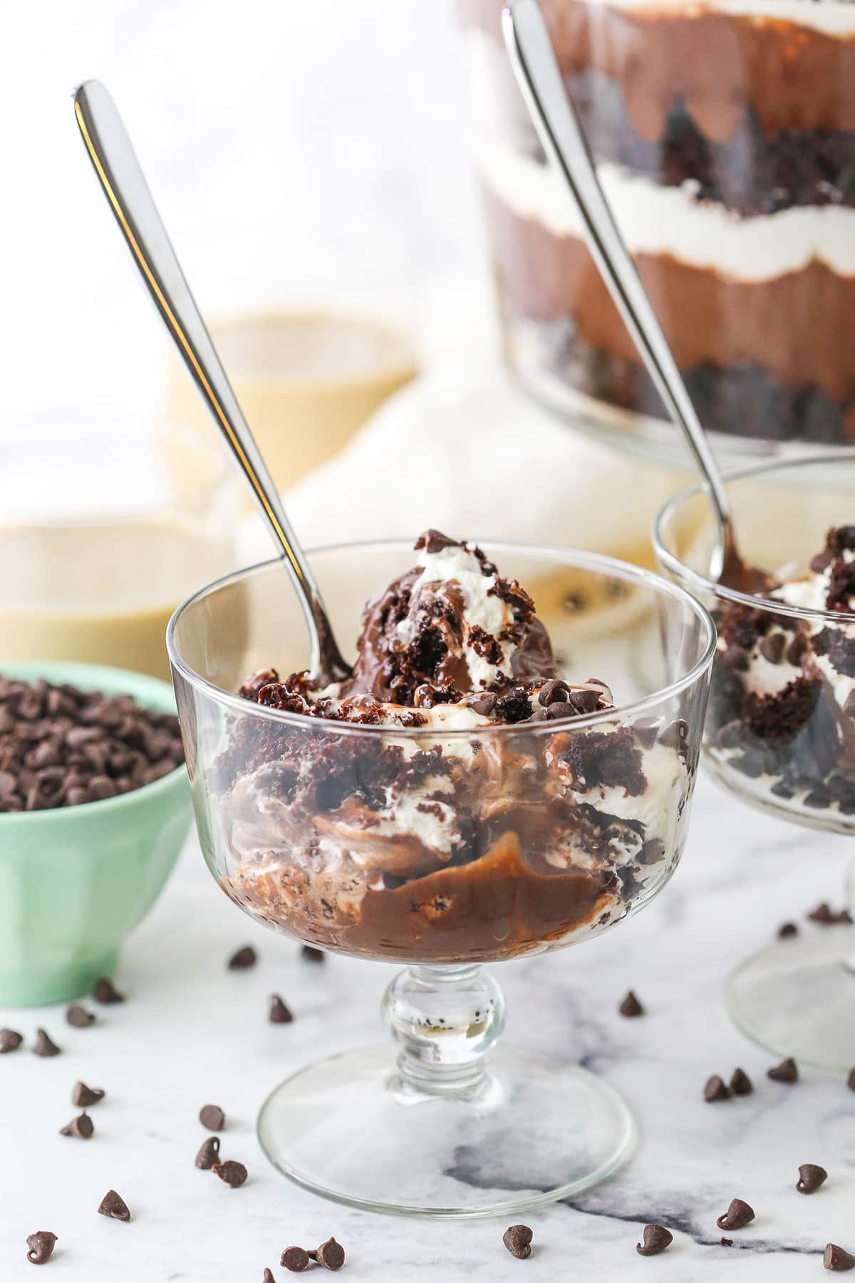 Two individual servings of Boozy Baileys Chocolate Trifle in glass bowls with spoons