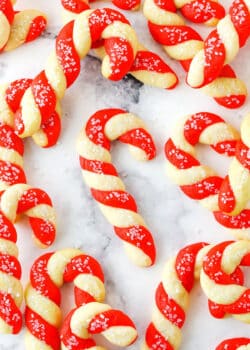 Red and white Candy Cane Cookies spread out on a white marble table top
