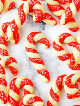 Red and white Candy Cane Cookies spread out on a white marble table top