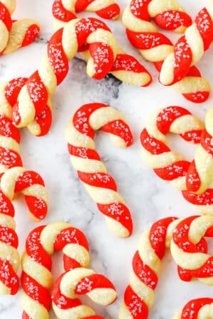 Red and white Candy Cane Cookies spread out on a white marble table top