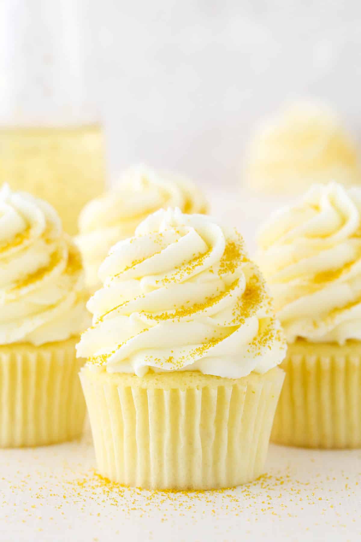 Four Champagne Cupcakes decorated with buttercream frosting on a white table top