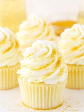 Four Champagne Cupcakes decorated with buttercream frosting on a white table top