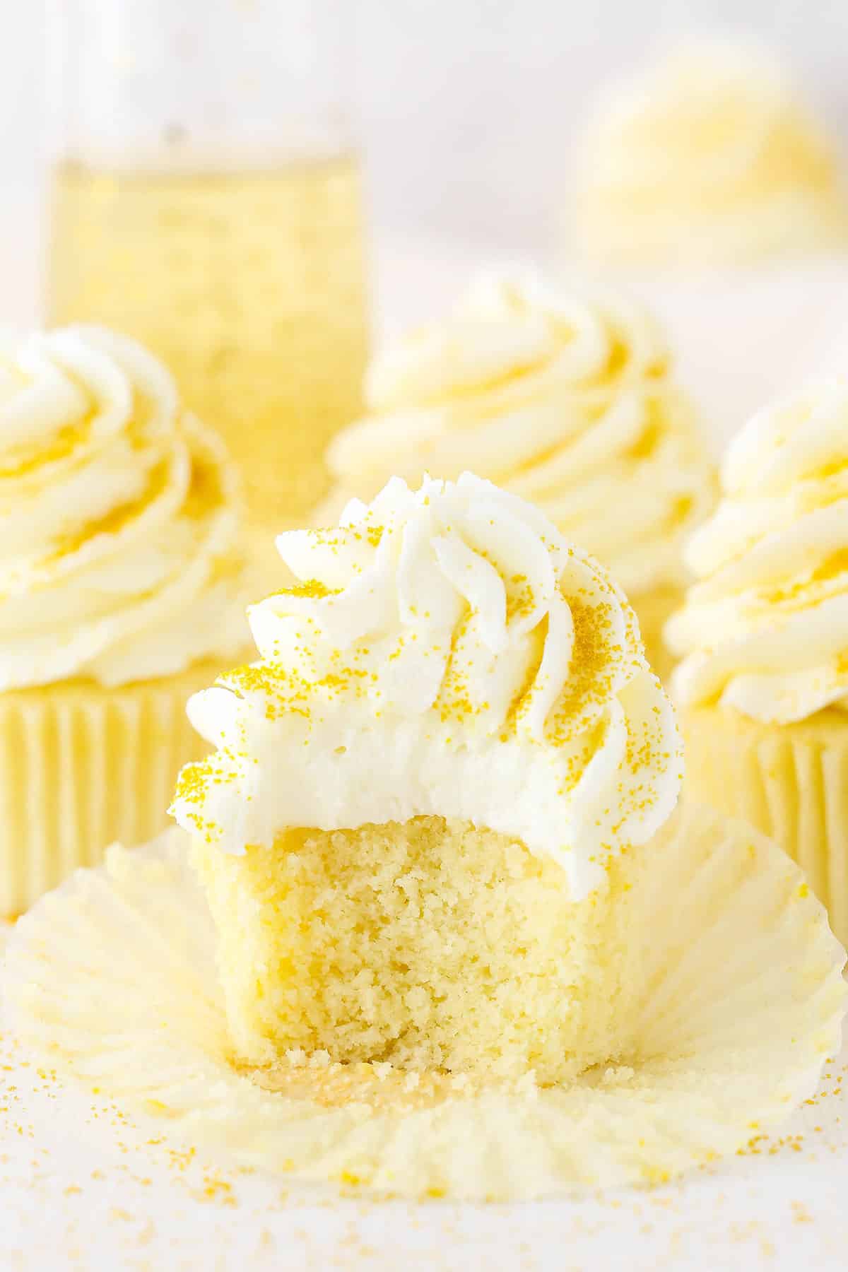 A Champagne Cupcake with a bite taken out and three more Champagne Cupcakes in the background