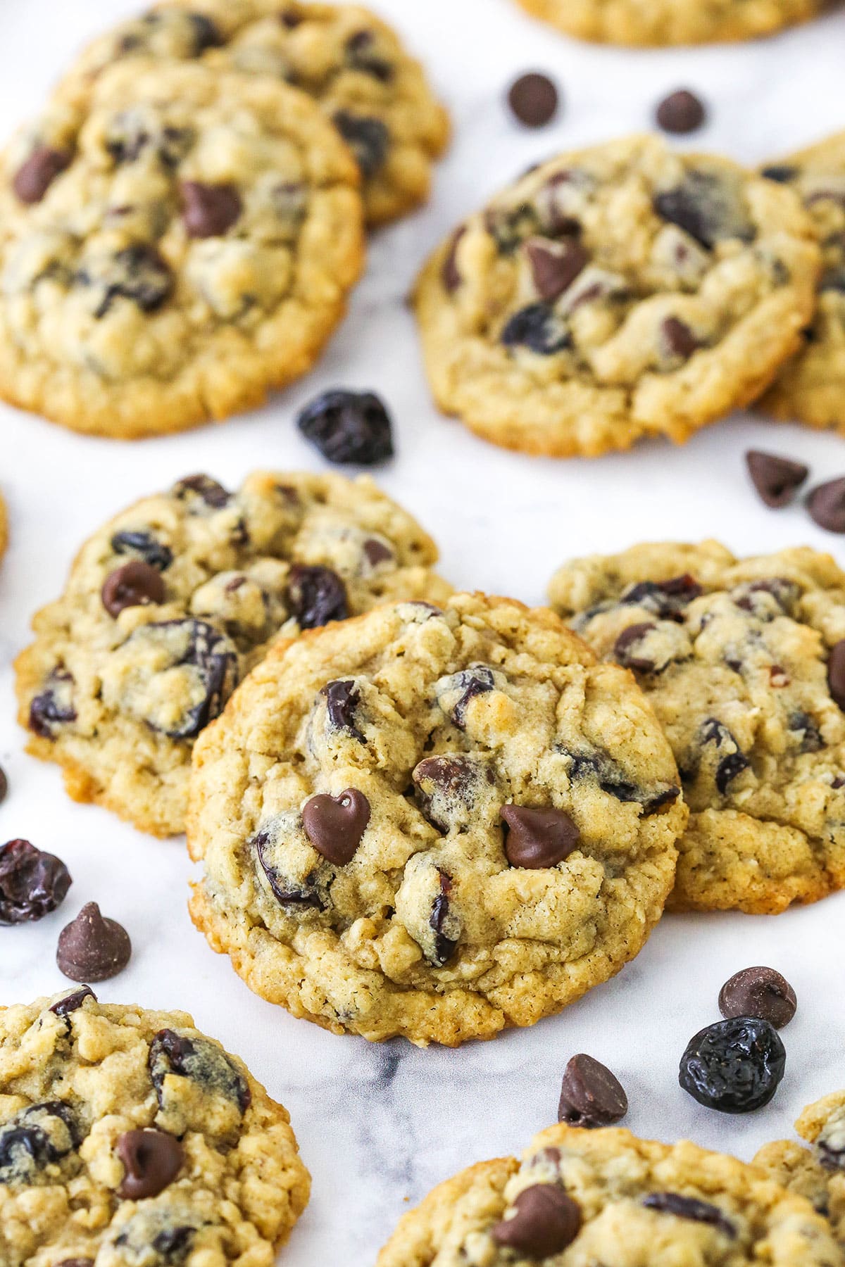 Overhead view of Cherry Chocolate Chip Oatmeal Cookies spread out on a white marble table top.