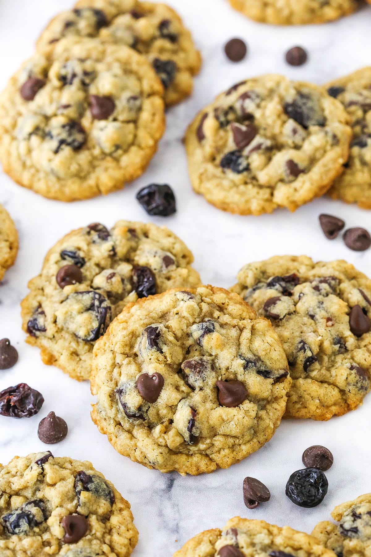 Overhead view of Cherry Chocolate Chip Oatmeal Cookies spread out on a white marble table top.