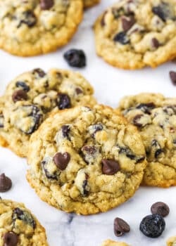 Overhead view of Cherry Chocolate Chip Oatmeal Cookies spread out on a white marble table top.