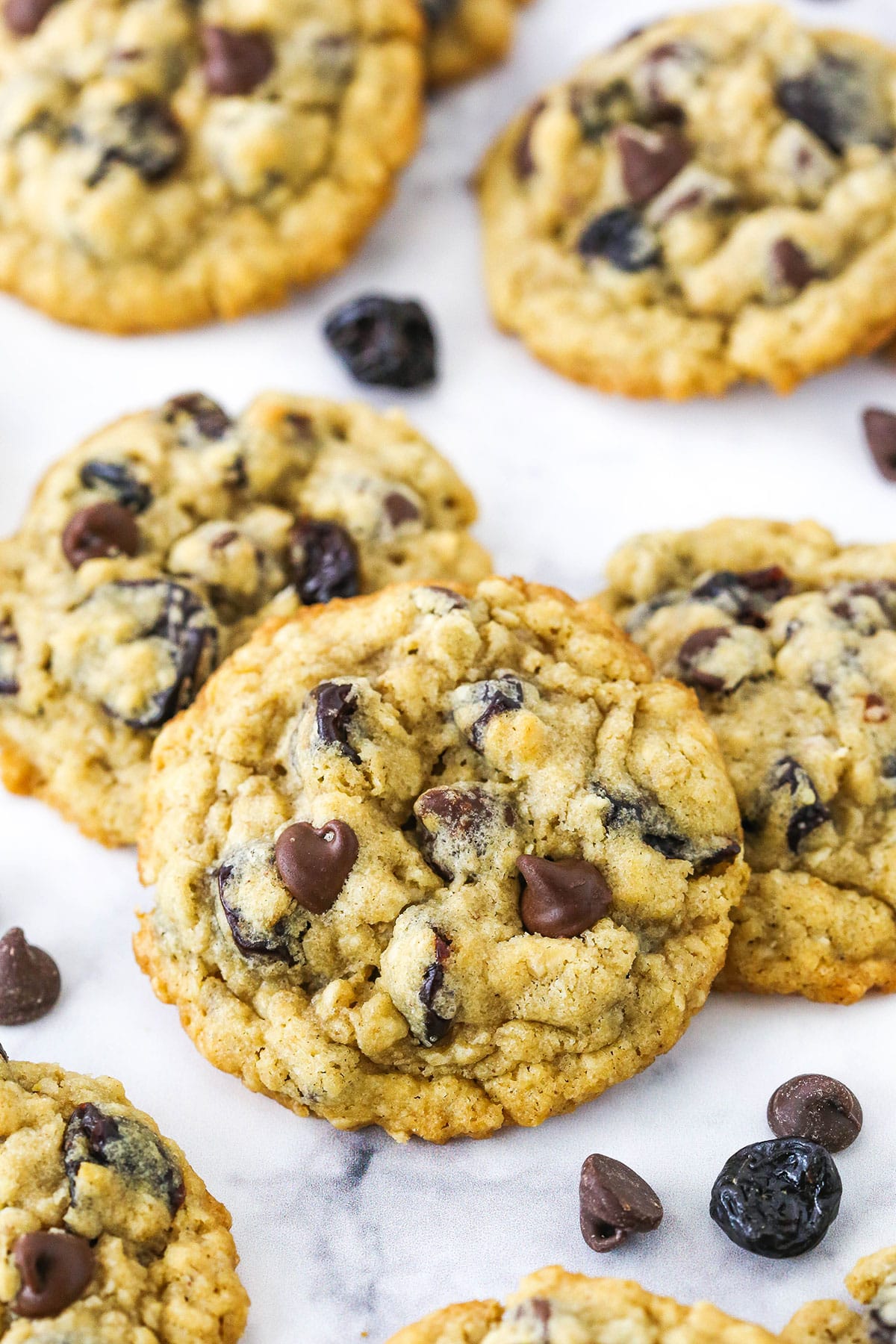 Overhead view of Cherry Chocolate Chip Oatmeal Cookies spread out on a white marble table top.