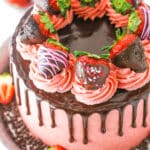 Overhead view of a full Chocolate Covered Strawberry Layer Cake topped with chocolate drip, pink swirls and chocolate covered strawberries on a metal cake stand