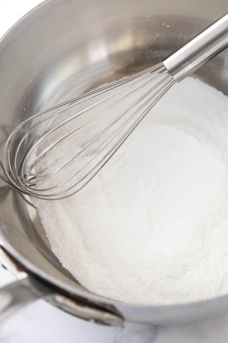 Whisking together sugar and cornstarch in a saucepan.
