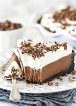 Chocolate cream pie on a plate with a fork taking a bite out of it.