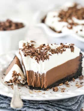Chocolate cream pie on a plate with a fork taking a bite out of it.