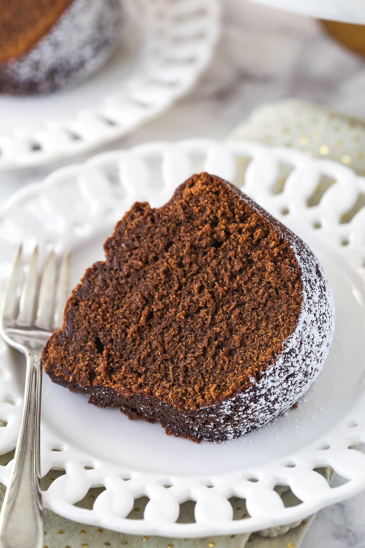 A slice of chocolate pound cake on a plate with a fork.