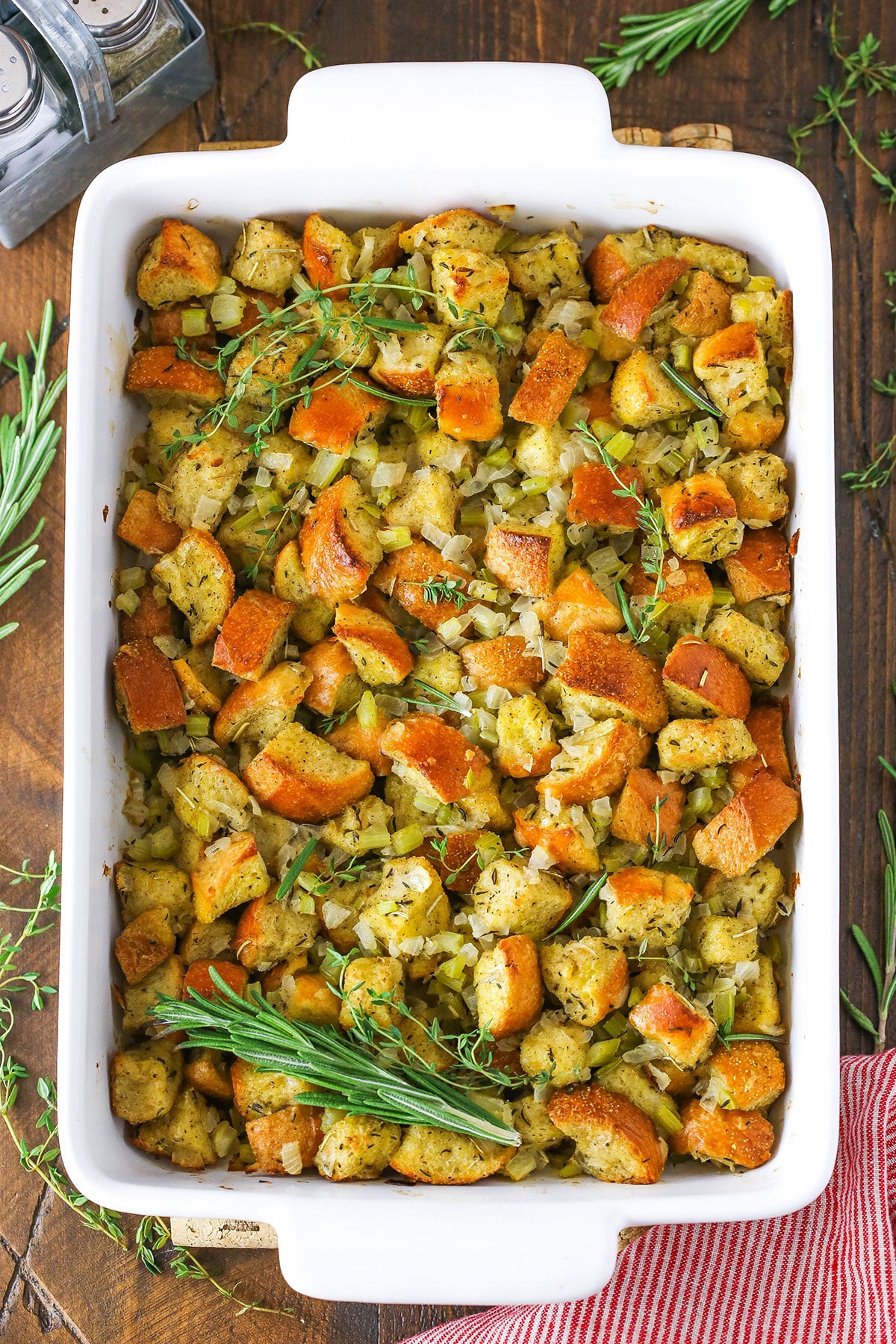 Overhead view of classic homemade stuffing in a white serving platter on a wooden table.