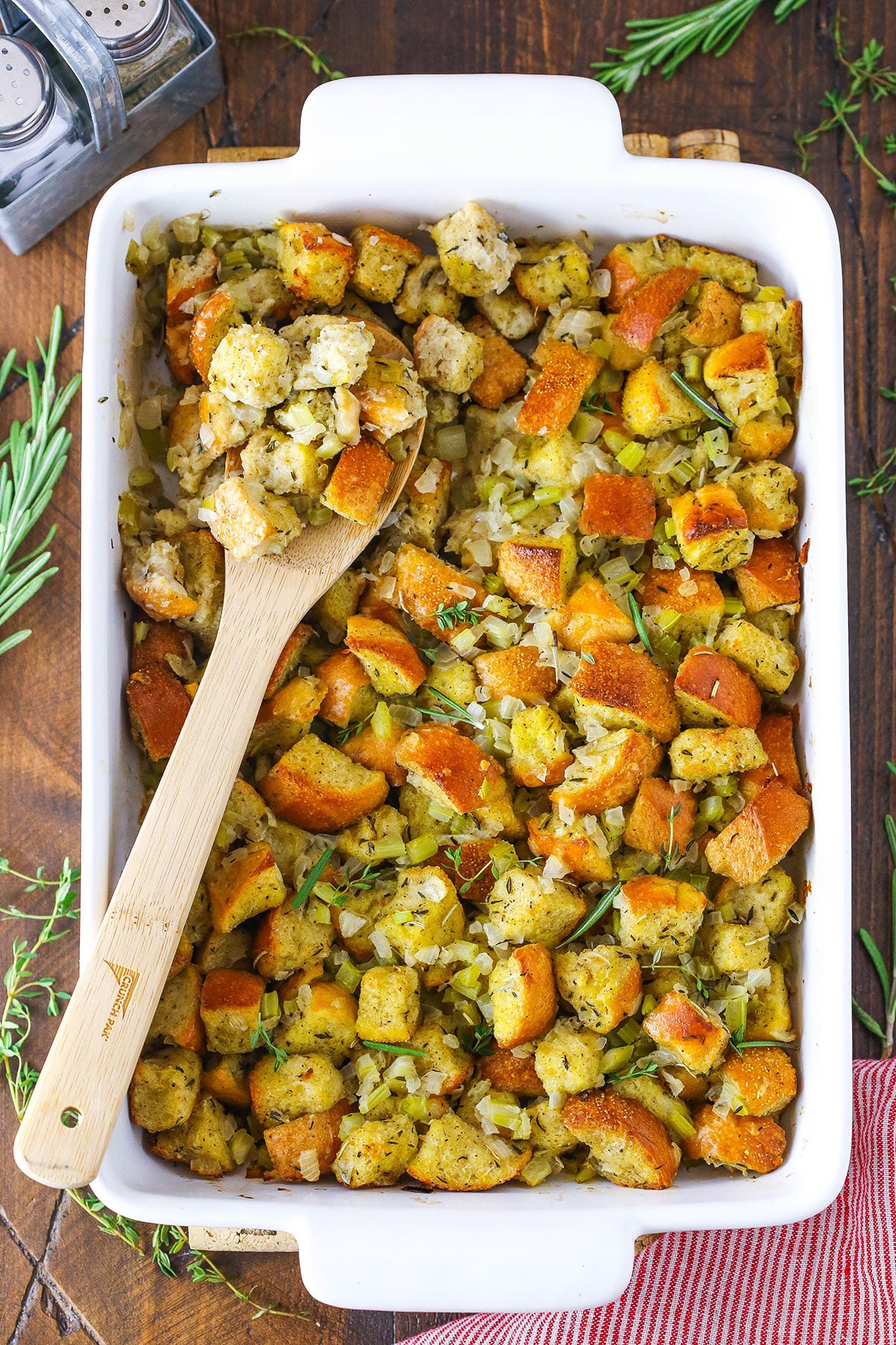 Stuffing in a white serving platter with a wooden spoon.