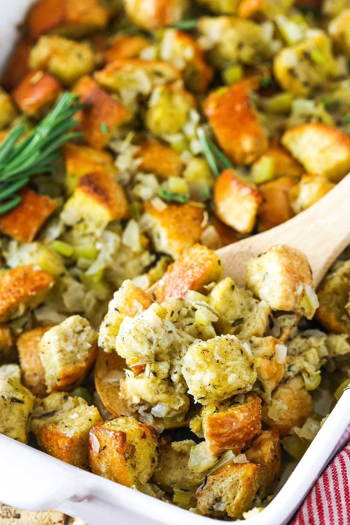 Homemade stuffing in a white serving platter with a wooden spoon.