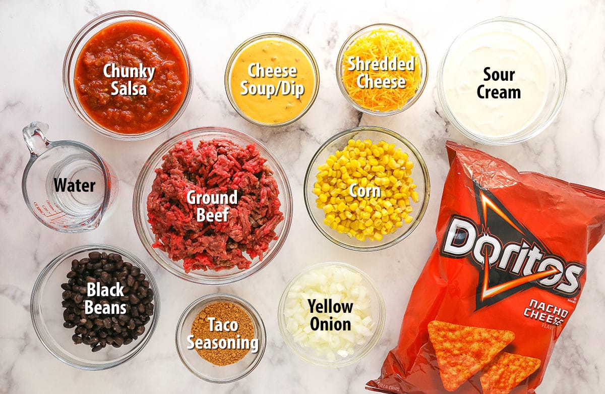 This Dorito casserole is made with layers of Doritos, ground beef, cheese, black beans, and corn and is packed with taco flavor. Ingredients for Dorito casserole separated into bowls.