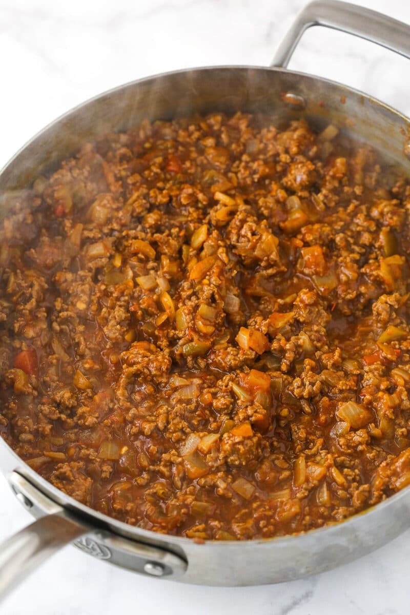 This Dorito casserole is made with layers of Doritos, ground beef, cheese, black beans, and corn and is packed with taco flavor. Simmering ground beef, onions, taco seasoning, water and salsa in a sauce pan.