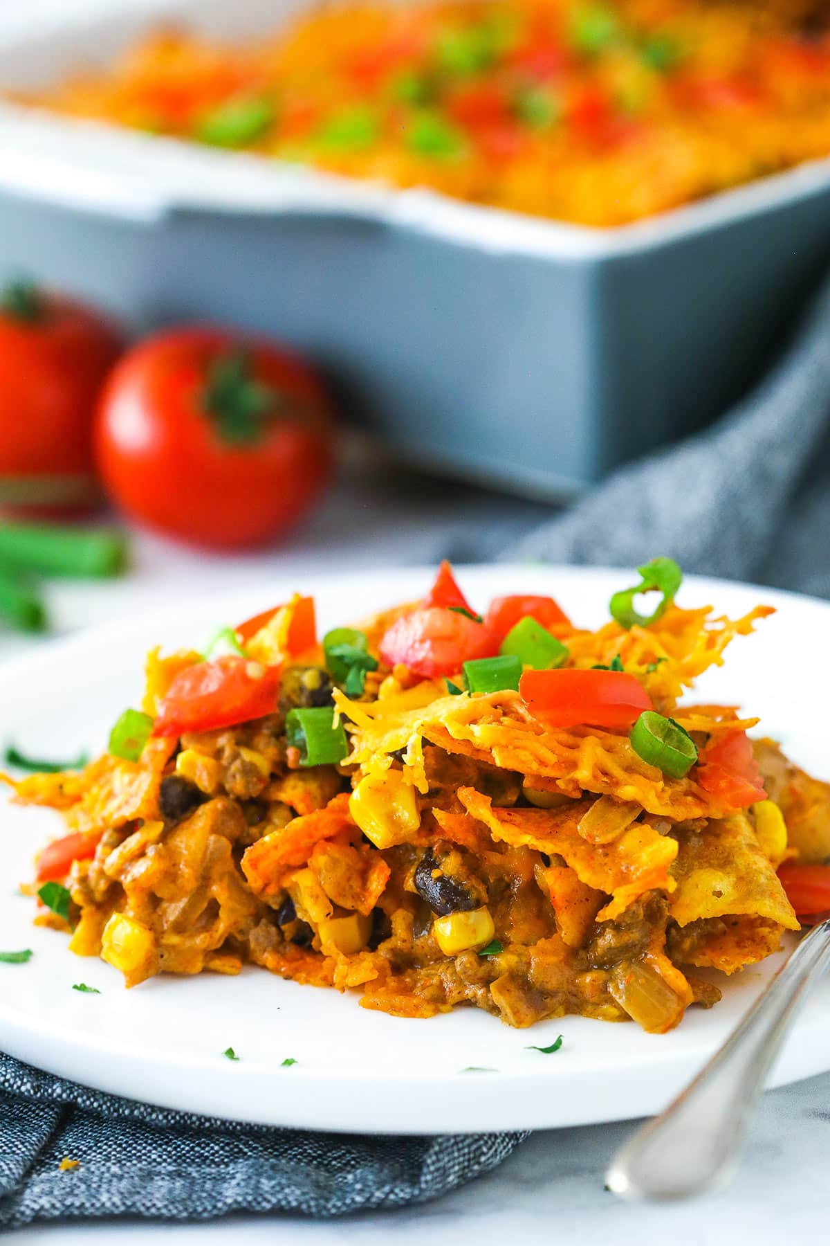 A slice of Dorito casserole on a plate with a fork.