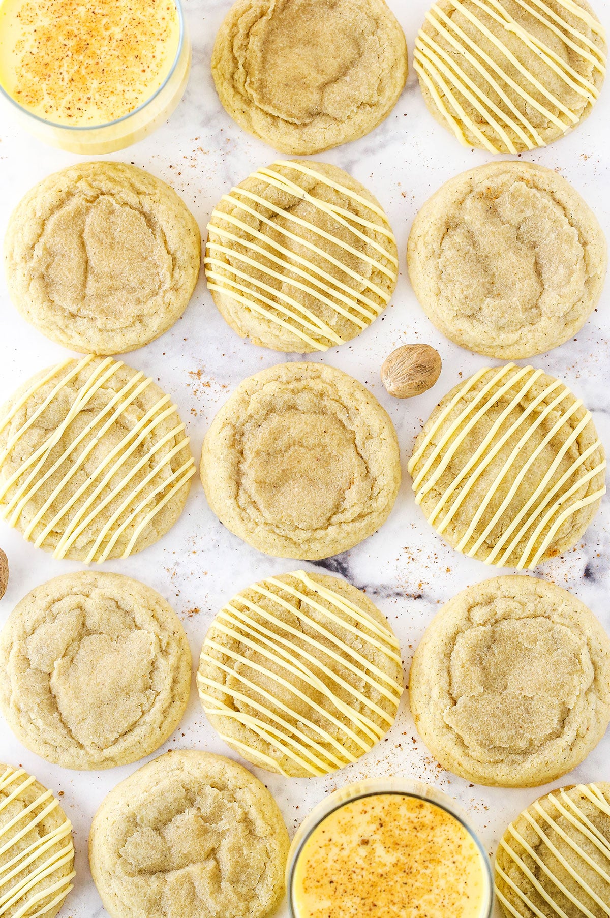 Overhead view of Eggnog Cookies and glasses of eggnog on a white marble table top